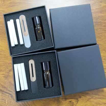 The Obsidian kit: fragrance sticks, roller bottle, and clip, shown with their packaging boxes open.
